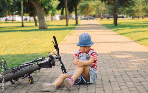 Fotografia Teenager kid girl fell off a bicycle and injured her knee outdoors in park