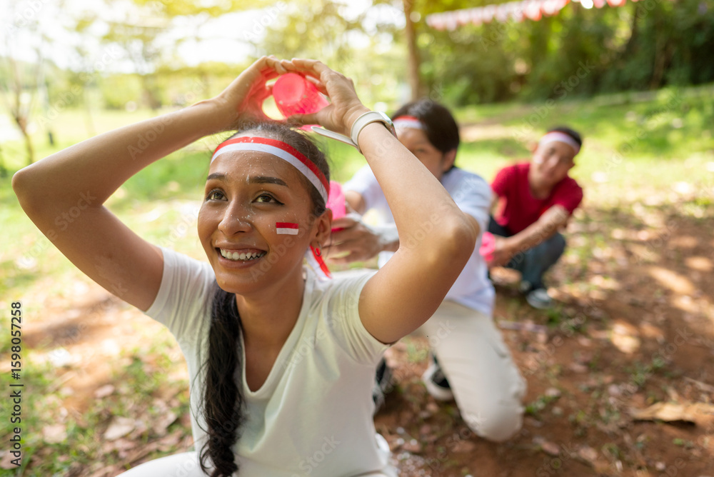Obraz premium Portrait of an Indonesian southeast asian people celebrate Indonesia Independence Day on the 17th of August with a game of moving flour with plastic glasses outdoors. Concept of Kemerdekaan Indonesia