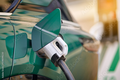 Canvas Print Closeup view of charger plug connected to green electric car charging port, eco transport and clean energy technology for sustainable urban mobility