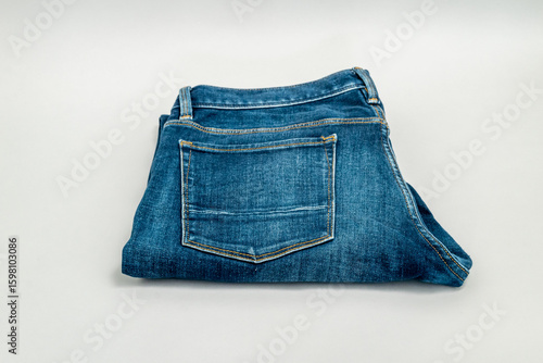 Single pair of blue jeans folded and isolated on grey background.
