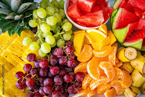 Tropical fruit charcuterie board fruits background, tray plate, light white floral background. Vegan food concept.