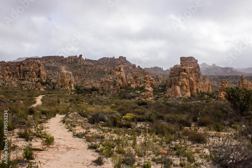 A hiking trail  winding through the strange rock sandstone formations of the Widow rocks in the Cederberg Mountains  South Africa  with rainclouds in the background