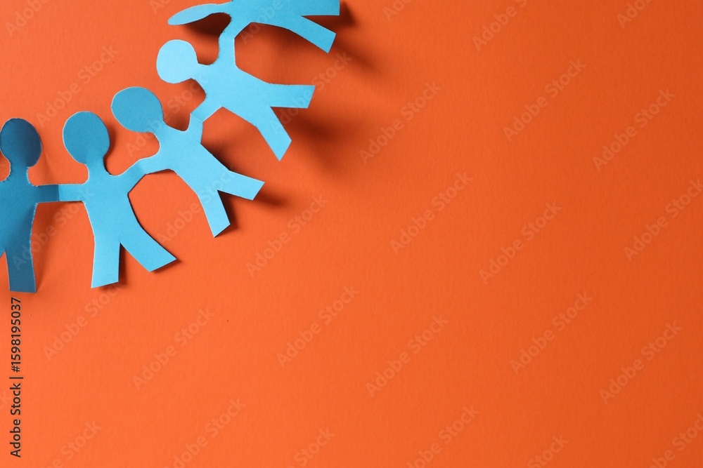 Fototapeta premium Paper figures of people holding hands on orange background, top view. Space for text