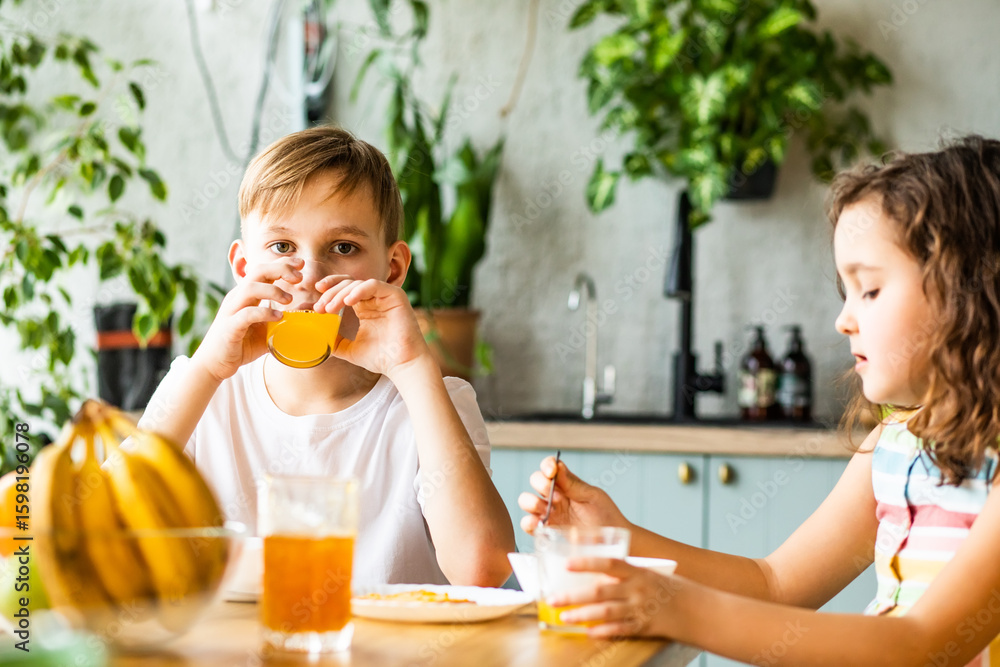 Happy family sister and brother have breakfast with cereal and milk in a kitchen at home Happy family sister and brother have breakfast with cereal and milk in a kitchen at home