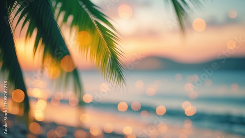 Blurred tropical beach scene with palm leaves and sunset lighting.