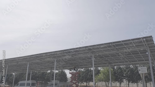 Workers installing solar panel structure using forklifts at a renewable energy site. Captured at solar canopy construction in Turkey. Ideal for sustainability, teamwork, and industrial process themes.