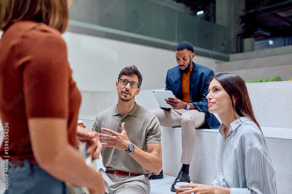 Fototapeta premium Group of young professionals engaging in a lively discussion while sharing innovative ideas during a casual meeting in the office lobby