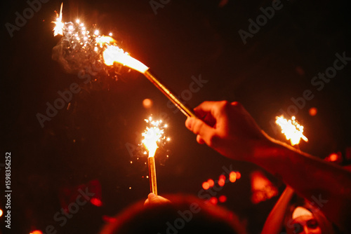 Hand Holding Sparkler in a Dark Crowded Nightclub Party