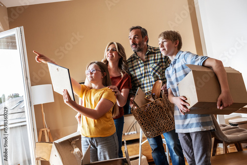 Fotografija A family is moving into a new apartment, unpacking boxes together in the living room