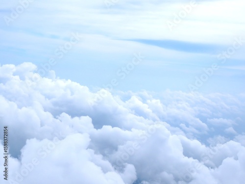 Fototapeta Naklejka Na Ścianę i Meble -  View from above the clouds showing a dreamy sky with soft, white cloud formations. Perfect for themes of travel, serenity, aviation, dreams, and nature.