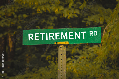 a green road sign reading RETIREMENT Road set against a blurred background of lush green foliage. financial design element, banner or background with copy space