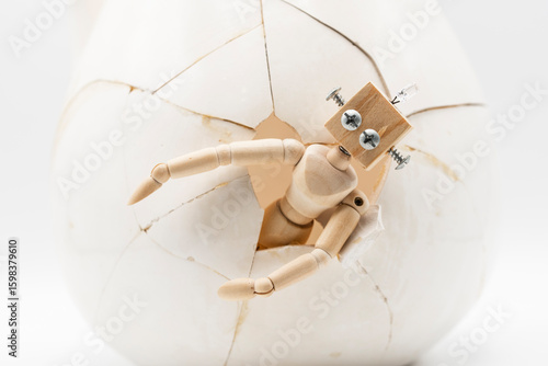 Maniquí de madera articulado con cabeza de robot saliendo de huevo, nacimiento de la inteligencia artificial