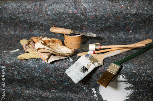 Konzept Renovieren, Lackieren, Streichen und Malen in einer Wohnung: Blick auf Pinsel, Farbe, Kelle, Spachtel, Handschuhe, Abdeckung und weitere Utensilien auf Malervlies, Copyspace, selektiver Fokus