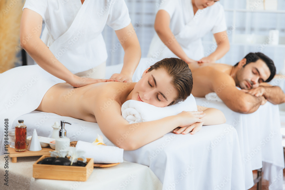 Obraz premium Caucasian couple customer enjoying relaxing anti-stress spa massage and pampering with beauty skin recreation leisure in day light ambient salon spa at luxury resort or hotel. Quiescent