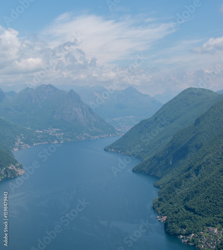 Aerial view of a mountain lake with villages along the shoreline and hills in the background.