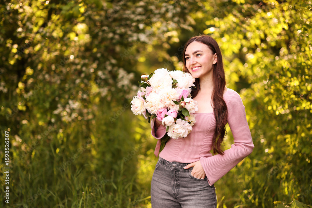 Beautiful woman with bouquet of peonies in park. Space for text Beautiful woman with bouquet of peonies in park. Space for text
