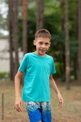 a boy child on a walk, wearing a turquoise T-shirt, standing sideways