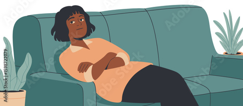 Woman sitting on a teal armchair with arms crossed looking thoughtful