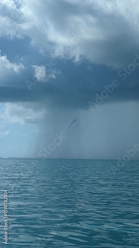 Waterspout forms over Gulf of Mexico ocean under cloudy sky