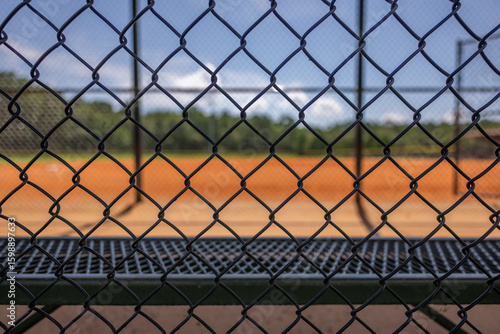 Looking through a chain link fence at an empty baseball field on a sunny day