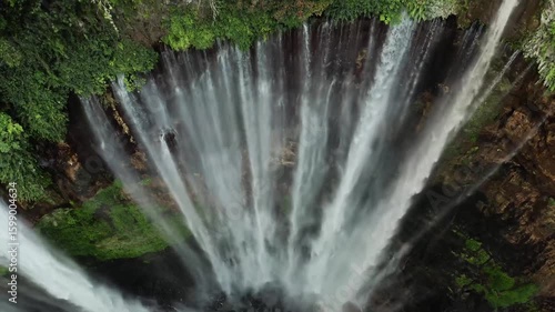 Aerial view of majestic waterfall cascading through lush green forest