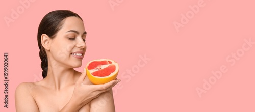 Beautiful naked young woman holding grapefruit on pink background with space ...