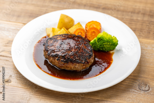 ソースがかかったハンバーグと温野菜の洋食プレート