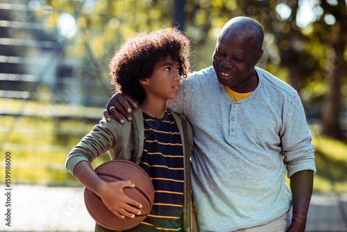 Grandfather and grandson bonding on basketball court outdoors