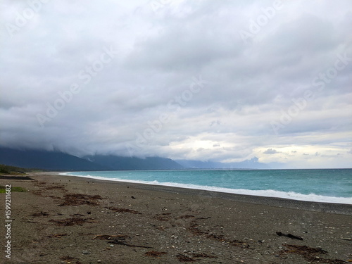 Qixingtan Beach with no people facing the wavy Pacific Ocean on a stormy day while clouds hovering on top of mountains at the back during the pandemic