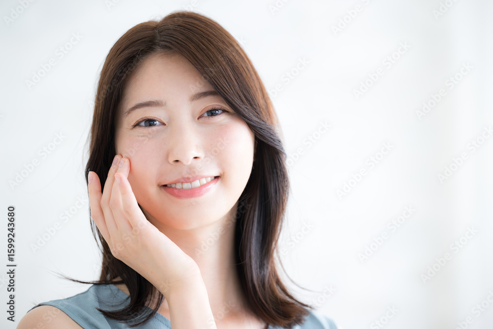 Naklejka premium 笑顔のかわいい女性 美容やビューティーのカメラ目線のクローズアップ 手を添える