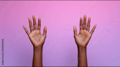 A Black person's hands held up with open palms against a pink background
