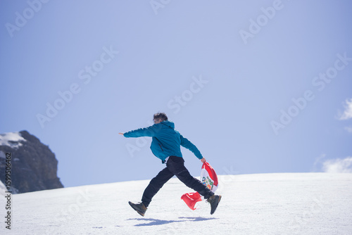 Man running down a snowy mountainside in the Andes with the Peruvian flag
