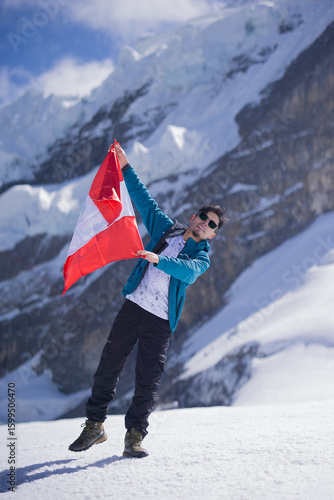 Man holding Peruvian flag on snowy Andes mountain