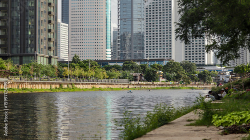 view of a public park with a lake in Jakarta in the morning with a background of modern buildings on the lake side