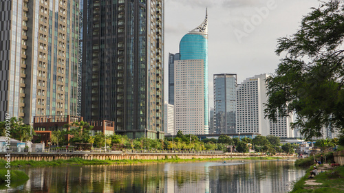 view of a public park with a lake in Jakarta in the morning with a background of modern buildings on the lake side