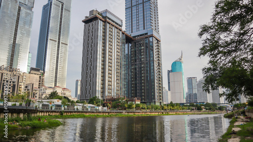 view of a public park with a lake in Jakarta in the morning with a background of modern buildings on the lake side