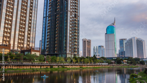 view of a public park with a lake in Jakarta in the morning with a background of modern buildings on the lake side