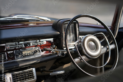 Vintage Classic car steering wheel, with chrome and leather textures in sharp detail, showcases the quality and precision of automotive craftsmanship under natural light.