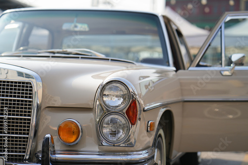 The round headlights and side turn signals on classic cars, framed in polished chrome, highlight the vintage style with old-fashioned lighting and curved fender details.