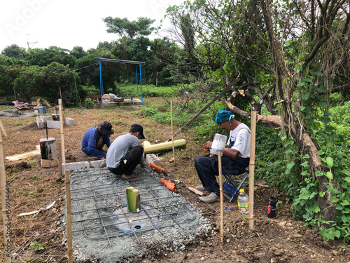Construction workers are pouring a concrete mixture onto the slab of a septic tank.