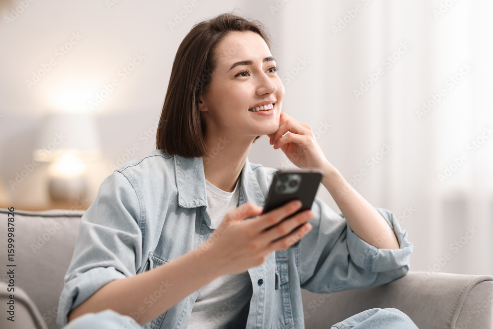 Woman using modern smartphone in armchair at home Woman using modern smartphone in armchair at home