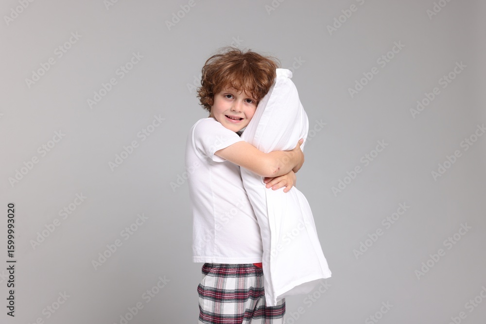 Cute little boy in pajamas with pillow on grey background Cute little boy in pajamas with pillow on grey background