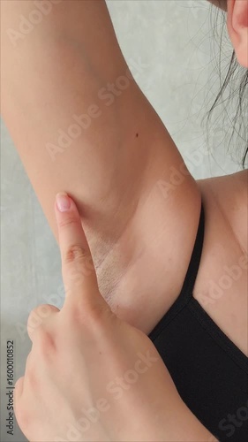 The woman points her finger at her armpit hair. Depilation of armpit hair.