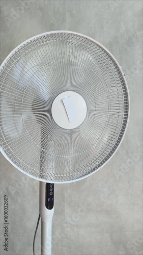 The fan blades rotate to cool the air in the heat of the room. The ventilator is turned on and the air is blowing.
