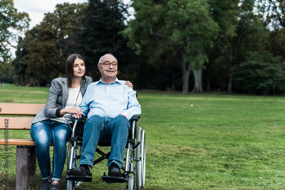 Companion providing care and support to wheelchair user in city park Companion providing care and support to wheelchair user in city park