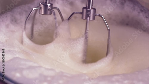 Close-up of whisk blades whipping egg whites until stiff peaks form. Smooth, 