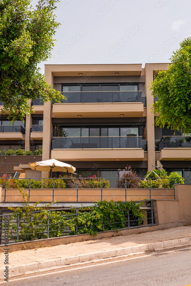 Fototapeta premium Modern apartment building with large balconies and greenery. structure features a contemporary design and is surrounded by trees