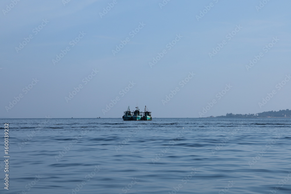 Obraz premium Tranquil Ocean Scene with Distant Fishing Boats at Dawn