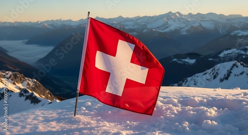 The Swiss flag waving proudly atop a snowy mountain peak with an expansive mountain range in the background.