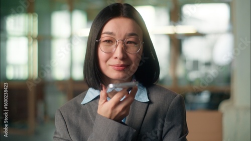 Tableau sur toile Businesswoman smiling record audio message send voice mail in office Asian busin